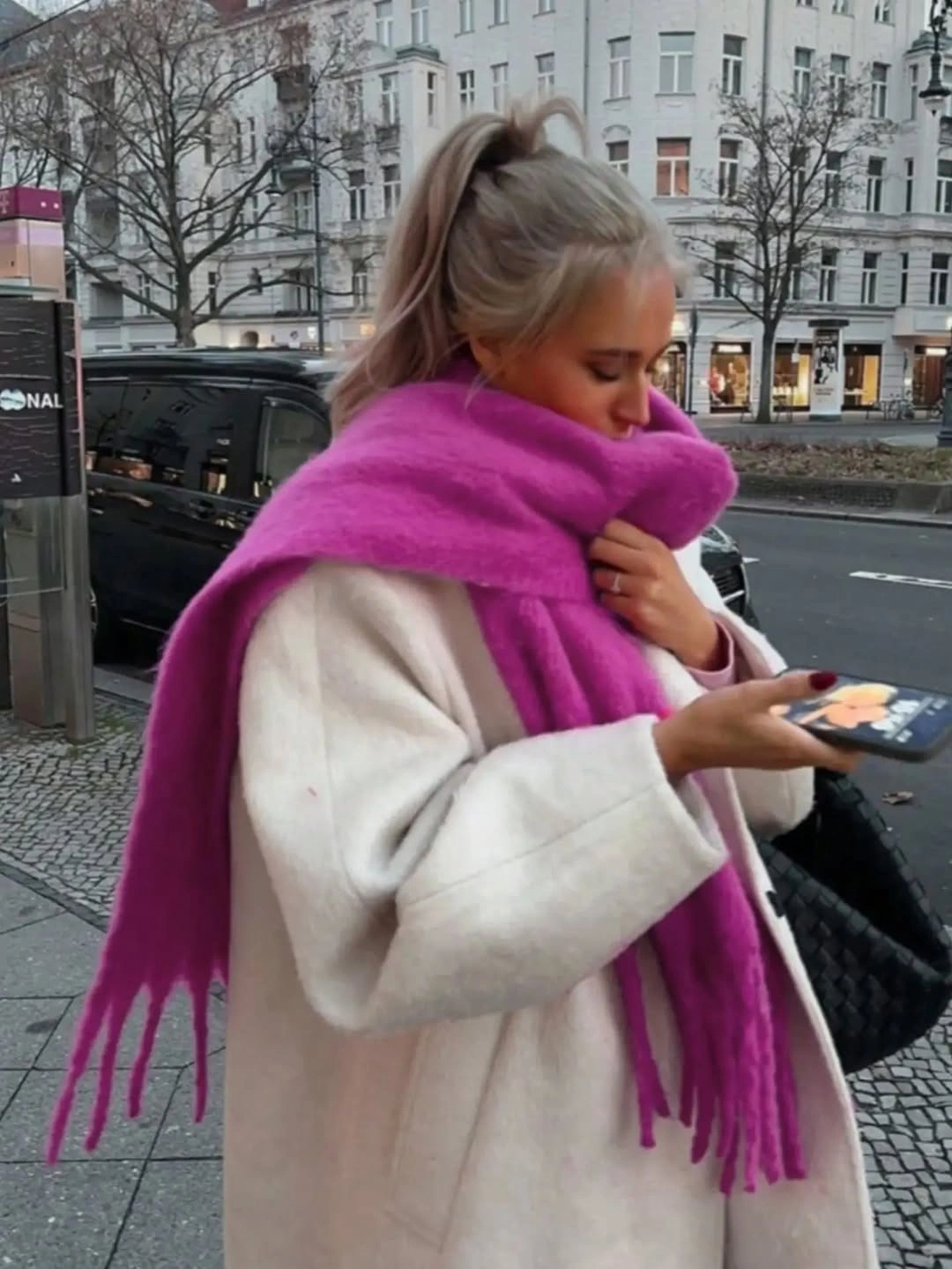 Ivory coat with oversized bright pink fringed scarf and black quilted bag