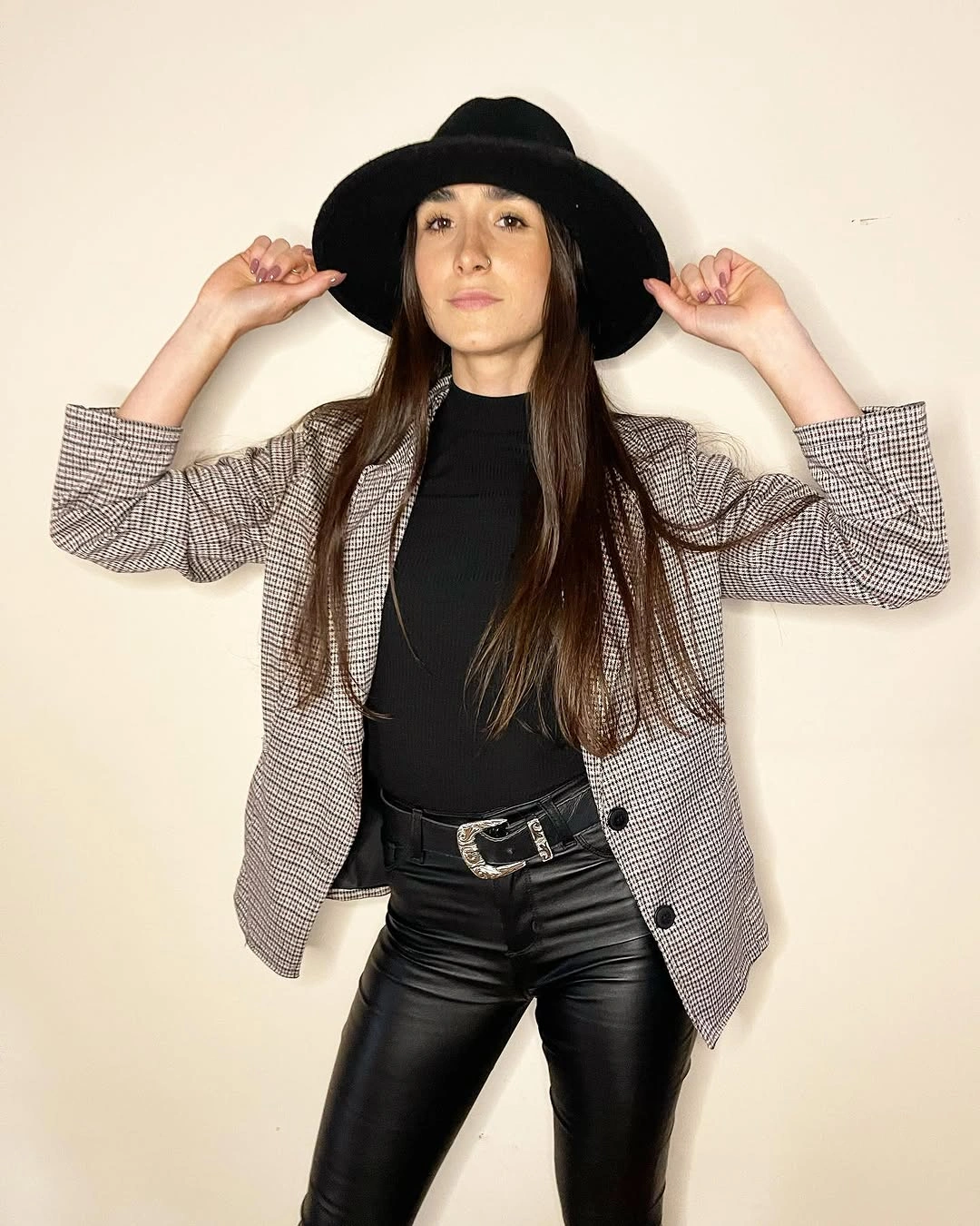 Gray checked blazer with black hat high-neck top and glossy pants